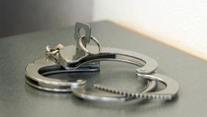 Bild: Armin Weigel/dpa
Handschellen liegen auf einem Tisch.