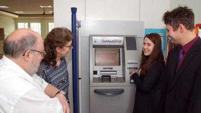 Bild: bkr
Gestern wurde der Geldausgabeautomat nach dem Einbau in Betrieb genommen. EDV-Chef Siegmar Kirsch (links) hat ihn programmiert, Lena Kohl (Zweite von rechts) durfte ihn testen. Zufrieden mit dem Ergebnis waren Helga Hofweller (Zweite von links) und Geschäftsstellenleiter Matthias Fütterer.