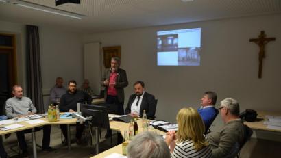 Bild: gi
Wolfgang Meidenbauer (stehend) und Adrian Wenck (Dritter von links) vom LTO informieren die Gemeinderäte über ihr Vorhaben der Belebung des früheren Raiffeisengebäudes.