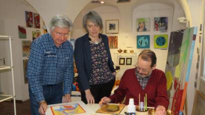 Bild: ubb
Der Künstler Tom Brankovic aus Schönkirch im Landkreis Tirschenreuth zeigt den Besuchern des OKV-Kunstkaufhauses bei "Sonna", wie Ikonen gemalt werden. Auch OKV-Vorsitzende Irene Fritz und Künstler-Kollege Uwe Müller (v. li.) schauen interessiert zu.