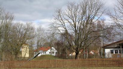 Bild: bjp
Zwischen dem alten Kindergarten (rechts), der abgerissen wird, und der Hauptstraße wird die neue Kindertagesstätte entstehen. Eine voll ausgestattete Küche soll sie nicht erhalten: Vor allem rigide Hygienevorschriften, Kosten- und Personalfragen legen einen Essensbezug von Caterern nahe.