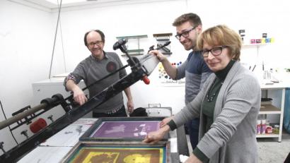 Bild: Hirsch
Der druckgrafische Künstler Bernd Hofmann (links) führte Marie Luise Pfeifer und deren Sohn Daniel aus Nabburg in die Geheimnisse des Siebdruckverfahrens ein.