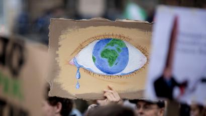 Bild: Christoph Soeder/dpa
Ein weinendes Auge mit der Erde als Iris bei einer Kundgebung "Fridays for Future".