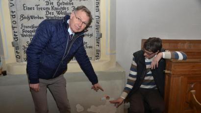 Bild: dob
Es ist zum Verzweifeln: zur geplanten Kirchendachsanierung kommen noch viel größere Mängel im Inneren der Stadtkirche hinzu. Probebohrungen ergaben, dass im Sockel viel Feuchtigkeit vorhanden ist. Die Gesamtkosten sind noch gar nicht abzuschätzen. Stadtpfarrer Dieter Schinke (links) und der stellvertretende Vertrauensmann des Kirchenvorstands, Uli Münchmeier, zeigen eines der Bohrlöcher am Sockel.