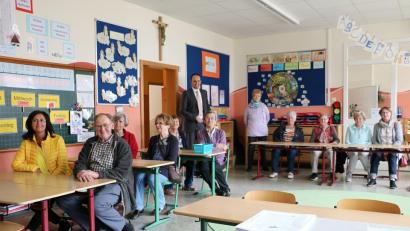 Bild: gru
Beim Besuch in der Schule nehmen die Senioren auch Platz auf den Stühlen der Erstklässler – und erinnern sich an die eigene Schulzeit.