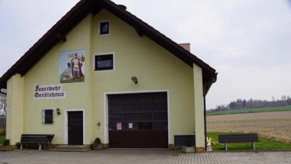 Bild: bkr
Nach rechts hin wird das Gerätehaus der Oberwappenöster Feuerwehr mit einem Schleppdach erweitert. Die grüne Fläche, auf der die Bank steht, nimmt den Anbau auf.
