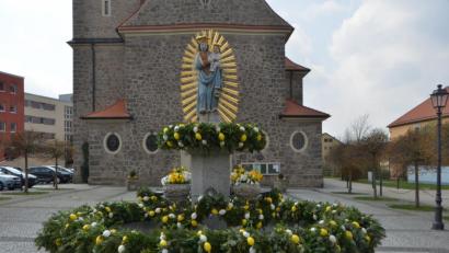 Bild: dob
Die Muttergottes mit dem Strahlenkranz hat auf dem Kirchplatz, dank des katholischen Frauenbunds, wieder ein österliches Schmuckkleid an. Der Brunnen wurde richtig herausgeputzt für die Osterfesttage.