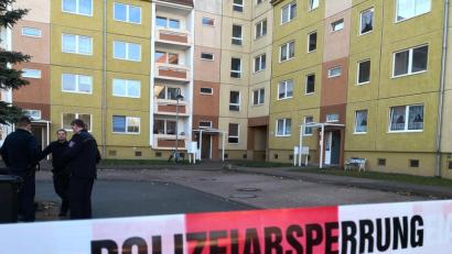 Symbolbild: Kathleen Sturm/dpa
Ein rot-weißes Absperrband mit der Aufschrift "Polizeiabsperrung" vor einem Wohnblock.