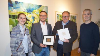 Bild: du
Klaus Kuran (rechts) und Tochter Susanne (links) überreichen bei der Vernissage in Schirmitz an Bürgermeister Ernst Lenk und Kulturkreischef Franz Hermann Beckmann Erinnerungsgeschenke in Form von "Akanthus"-Linolschnitten.