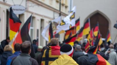Bild: Arno Burgi/dpa
Ein Mann mit einer Fahne mit dem Logo der "Identitären Bewegung" bei einer Demo in Sachsen.