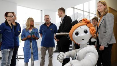 Bild: Wolfgang Steinbacher
Bei der dritten Roadshow zur Digitalisierung im Siemens-Gerätewerk waren erstmals externe Experten dabei. Hier präsentiert die OTH ihren humanoiden Roboter Pepper, der das Publikum mit dem Spruch „viel Spaß beim Entdecken“ begrüßte. Pepper mit der je nach Emotion wechselnden Augenfarbe könnte bei Siemens etwa als Kommunikationswegweiser am Empfang Verwendung finden, sagt OTH-Professor Dominikus Heckmann. „Aber für die Produktion fehlt ihr die Kraft.“ In Kinderbetreuung und Altenpflege hat Pepper „schon super eingeschlagen“.