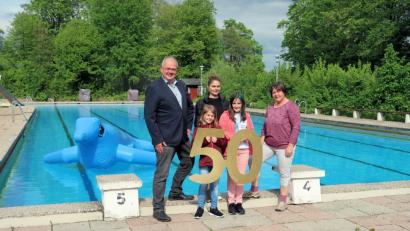 Bild: bsc
50 Jahre Friedenfelser Freibad: Über den Start in die Jubiläumssaison freuen sich Lisa Rauh (rechts) und Katharina Fleischmann (Mitte) sowie Bürgermeister Gottfried Härtl (links). Der fünf Meter große Seehund „Robby“ (hinten) ist bereits der Freund von Alisa und Christina (vorne von links).