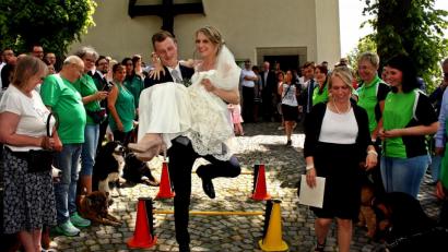 Bild: zer
Daniel Flierl trägt seine Braut Elisa durch den Hindernisparcours, den die Hundefreunde aus Weiden aufgebaut hatten. Viele weitere Vereine gratulieren den beiden Mantelern vor der St.-Felix-Kirche.
