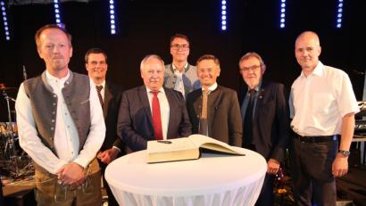 Bild: hwk
Neben den Geschäftsführern Alexander Remes (links) und Ralf Zander (Vierter von links) sprechen auch Florian Rieder, Hermann Brandl, Tobias Reiß, Josef Etterer und Arne Köhler (von links) Grußworte zu dem rund 400 Jubiläumsgästen. Anschließend tragen sie sich ins Goldene Buch der Gemeinde ein.