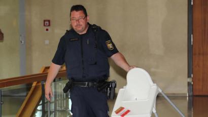 Bild: ca
Ein Justizwachtmeister bringt den Kinderstuhl, auf dem die Tasse mit heißen Tee stand, mit dem sich das Kind verbrühte - wenn man die Variante der Mutter glaubt.