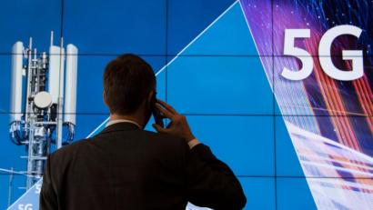 Bild: Boris Roessler/dpa 
Ein Mann steht im Gebäude der Bundesnetzagentur vor einer Leinwand mit der Aufschrift 5G.