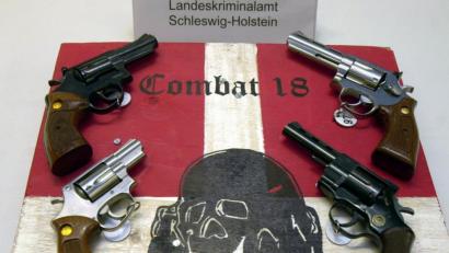 Bild: Horst Pfeiffer/dpa
Sichergestellte Waffen und ein Schild der Neonazi-Gruppe "Combat 18" liegen im schleswig-holsteinischen Landeskriminalamt (LKA).