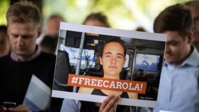 Bild: Federico Gambarini/dpa 
Nordrhein-Westfalen, Köln: Eine Demonstrantin hält ein Bild von der Sea-Watch-Kapitänin Carola Rackete mit der Aufschrift "#FREECAROLA!" in der Hand. Mit einer Mahnwache haben am Dienstag etwa 100 Menschen vor dem italienischen Generalkonsulat in Köln für die Freilassung von Sea-Watch-Kapitänin Carola Rackete demonstriert.