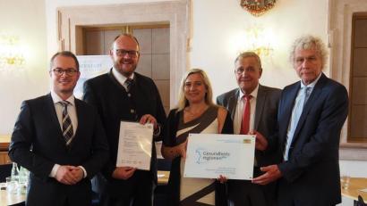 Bild: Bühner
Professor Steffen Hamm (von links) und Landrat Andreas Meier nehmen von Ministerin Melanie Huml die Urkunde für die „Gesundheitsregion“ entgegen. Das 5G-Projekt ist ein neuer Schritt