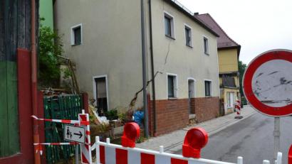 Bild: ll
Weder für Fahrzeuge noch für Fußgänger wird es vorerst an dieser Stelle der Auerbacher Straße ein Durchkommen geben. Der Grund sind die Gefahren, die durch das möglicherweise einsturzgefährdete Haus mit einem großen Riss in der Fassade entstehen.