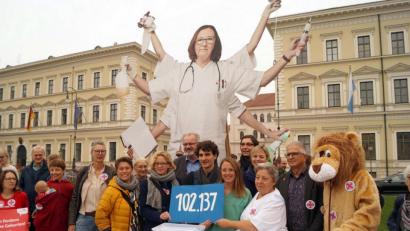 Bild: Stefan Jagel
Natascha Kohnen (SPD) , Ates Gürpinar (Linke) und Pflegekräfte halten ein Schild mit der Zahl 102 137