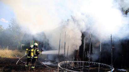 Bild: jma
Die Atemschutzträger bei der Brandbekämpfung. Neben der Hütte wurden auch einige Spielgeräte, zum Beispiel ein Trampolin, Opfer der Flammen.