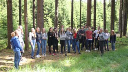 Bild: den
Die Klasse 10b bei der "Zielansprache" einer ausgewählten Fichten-Baumkrone, deren Schadbild auf einen Nadelverlust von rund 30 Prozent hindeute, so Revierleiter Karl-Heinz Melzer (rechts, im Vordergrund).