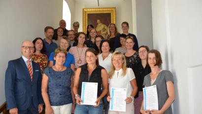Bild: Regierung der Oberpfalz/Stühlinger)
Bereichsleiter Thomas Unger (vorn, links) und Sieglinde Glaab (rechts daneben), ehemals Schulamtsdirektorin der Staatlichen Schulämter im Landkreis und in der Stadt Regensburg, bei der Zertifikatsübergabe an der Regierung der Oberpfalz.