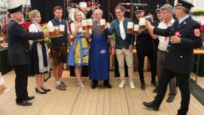 Bild: ral
Schirmherr Georg Köppl (mit Schürze) stößt mit Alois Plößl (rechts daneben), Bierprinzessin Lena (links daneben), den Verantwortlichen der Feuerwehr und stellvertretendem Landrat Jakob Scharf (Zweiter von rechts) auf das 125-jährige Gründungsfest der Feuerwehr Fronhof an.