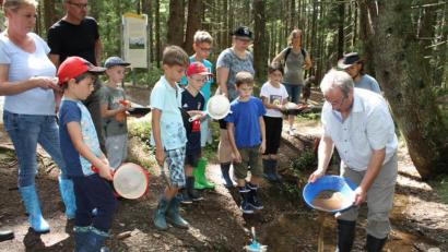 Bild: lg
Auf der Suche nach Gold schwenkt Karlheinz Pieper (rechts) die mit Sand und Kies gefüllte Waschpfanne. Gespannt verfolgen die Teilnehmer den Vorgang des Auswaschens der Sedimente.