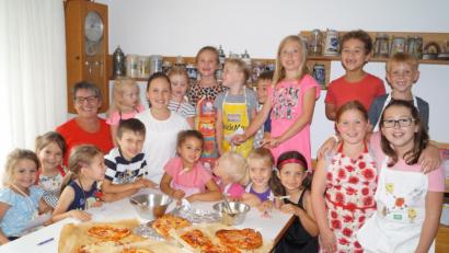 Bild: du
Stolz präsentieren die 15 Kinder mit Kursleiterin Doris Bock (hinten, links) ihre Pizza-Kreationen, die anschließend in den Backofen wandern.