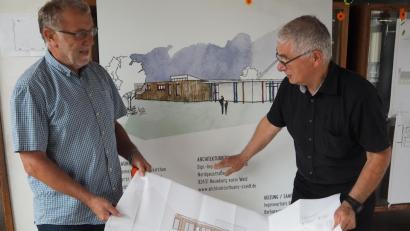 Bild: bl
Bürgermeister Hans Graßl und Architekt Michael Steidl (rechts) sind gespannt auf den Kindergarten-Neubau (Skizze im Hintergrund) mit Holzelementen, die sich wie Legoteile ganz schnell zusammenfügen lassen.