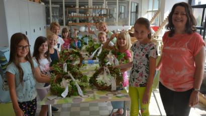 Bild: jr
Acht Bastelkurse hat Nicole Schuller (rechts) heuer für das städtische Ferienprogramm organisiert. Das Bild zeigt sie mit den Teilnehmern des Kurses mit dem Titel „Sommerkranz für die Tür mit Spitze“.