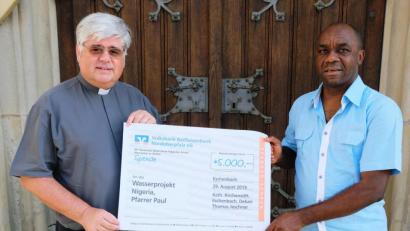 Bild: do
7000 Euro spenden die Gläubigen der Pfarrei Eschenbach für das Wasserprojekt von Vikar Chinedu Paul Ezenwa: Stadtpfarrer Thomas Jeschner überreicht einen Spendenscheck in Höhe von 5000 Euro im Namen der vielen Spender, weitere 2000 Euro erhält der Vikar an Direktspenden.