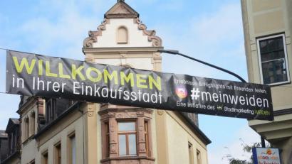 Bild: Gabi Schönberger
Das Banner in der Sedanstraße wirbt bereits für den Einkauf in „#meinweiden“. Die Hashtag-Aktion zählt zu den Maßnahmen, mit denen der Stadtmarketingverein für die NOC-Eröffnung, aber auch für die übrige Geschäftswelt, die Werbetrommel rührt.