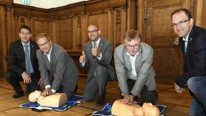 Bild: Petra Hartl
Bürgermeister Martin Preuß (Zweiter von links) und Klinikumsvorstand Manfred Wendl (Zweiter von rechts), zeigen wie’s geht: Die lebensrettende Reanimation will gelernt sein. Darum geht es bei der bundesweiten Woche der Wiederbelebung, wegen der auch Marc Bigalke (links), der Ärztliche Leiter der Zentralen Klinikums-Notaufnahme, Dr. Andreas Redel (Mitte) und Dr. Jens Schlör (rechts) ins Rathaus gekommen sind.