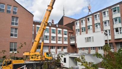 Bild: Andreas Royer
Insgesamt 13 Raummodule werden am St.-Anna-Krankenhaus für eine Interims-Küche innerhalb von zwei Werktagen im ehemaligen Patientengarten aufgestellt. Dazu gehören neben den Kochbereichen auch die Lagerhaltung, Spülküche, Speisenverteilung und Kühlräume.