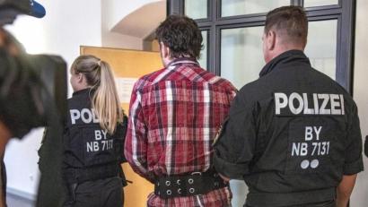 Bild: Armin Weigel/dpa 
Der Angeklagte wird von Polizisten in den Verhandlungssaal des Landgerichts geführt.