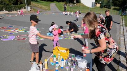 Bild: do
Künstlerisch einfallsreich und kreativ geht es zu beim nachgeholten Straßenmalen im Zuge des städtichen Ferienprogrammes. Zeitweise verwandeln bis zu 50 Mädchen und Buben den Straßenasphalt vor dem Kindergarten in eine bunte Blumen- und Buchstabenwiese.