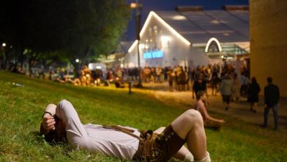 Bild: Tobias Hase/dpa
Platt: Ein Besucher in Lederhose liegt am Rande des Oktoberfests am Abend auf einer Wiese.