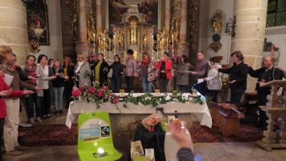 Bild: jzk
Beim Segenskreis hielt jeder die linke Hand geöffnet wie eine Schale. Die rechte Hand legte er behutsam auf die linke Schulter des rechten Nachbarn. So empfing jeder den Segen und gab ihn weiter. Vor dem Volksaltar waren fair gehandelte Waren aufgebaut.