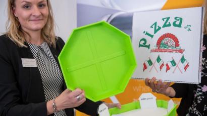 Bild: Daniel Karmann/dpa
Cornelia Fehlner von der Nürnberg Messe präsentiert das "Pizzabow". Ein Mehrwegsystem bestehend aus stapelbaren Kunststoffschalen, in denen sich ein Papptablett befindet. Der größte Teil der Pappe eines herkömmlichen Kartons wird somit überflüssig. Das Papptablett wird bei der Lieferung entnommen und behalten, die Schale wird wieder mitgenommen und wiederverwendet.