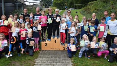 Bild: no
Die Kinder, die 2019 am Kinderlauftraining teilgenommen haben, mit den vier Eifrigsten am Siegerpodest, sowie den Trainern.