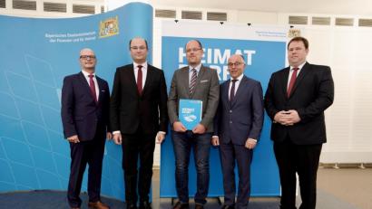 Bild: Bayerisches Staatsministerium der Finanzen und für Heimat/Christian Blaschka
Schwarzenbachs Bürgermeister Thorsten Hallmann (Mitte) darf mit stellvertretendem Landrat Albert Nickl (Zweiter von rechts) die Auszeichnung "Gütesiegel Heimatdorf" von Finanzminister Albert Füracker (Zweiter von links) entgegennehmen.