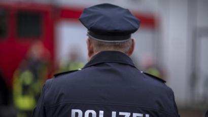 Bild: Jens Büttner/dpa
Polizisten stehen vor einem Polizeifahrzeug.