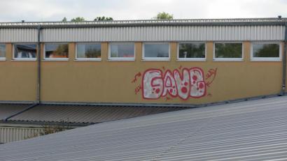 Bild: jzk
An die Außenfassade des Mittelschultraktes haben die Täter die Wörter „Gang“ und „slay“ gesprayt. Dazu mussten sie auf das Vordach beim Eingangsbereich steigen. Wie sie das geschafft haben, ist ebenso unklar wie deren Identität.