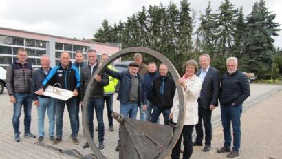 Bild: fg
Bildhauer Heinrich Glas (Mitte, mit Kappe) erläutert dem Bauausschuss des Hirschauer Stadtrats mit Bürgermeister Hermann Falk (Fünfter von links) an der Spitze das Kunstwerk "Wagenfragment - Goldene Straße“.