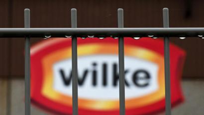 Bild: Uwe Zucchi
Wassertropfen hängen am Zaun vor dem Logo des nordhessischen Wurstherstellers Wilke. Die Waren von Wilke werden mit zwei Todesfällen und 37 weiteren Krankheitsfällen in Verbindung gebracht.