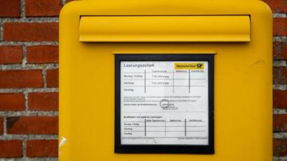 Symbolbild: Christian Charisius/dpa
Ein Briefkasten der Deutschen Post mit Leerungszeiten hängt an einer Hauswand.