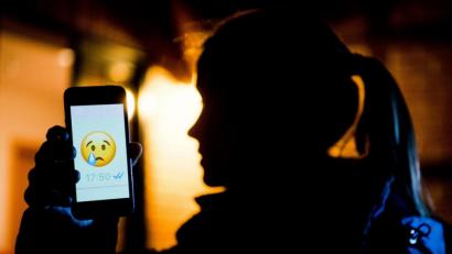 Symbolbild: Julian Stratenschulte/dpa
Ein junges Mädchen zeigt das Display eines Smartphones; darauf ein weinendes Emoji im Messenger Whatsapp.